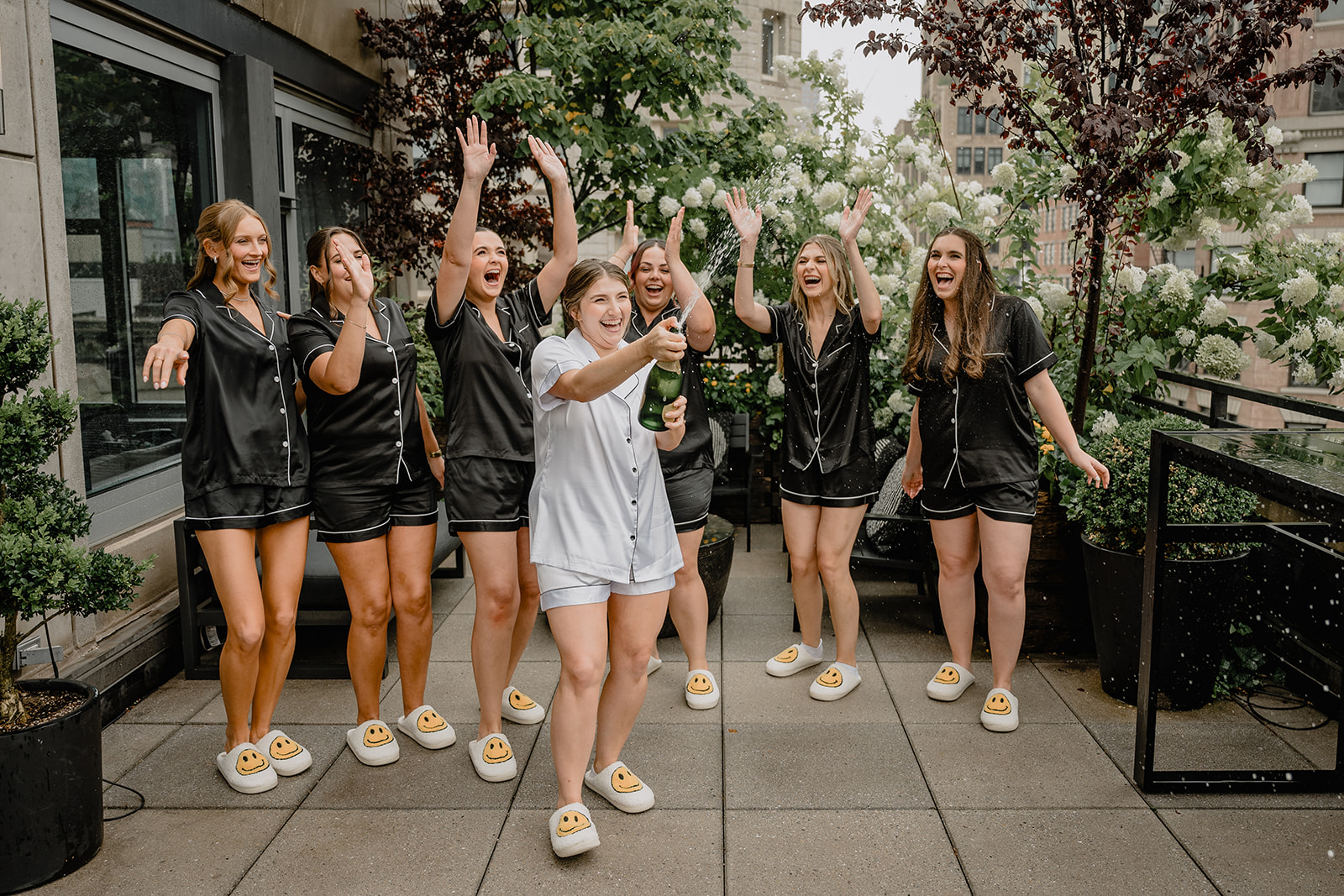 Bride opening a bottle of champagne with her bridesmaids before their intimate wedding at Tribeca Rooftop