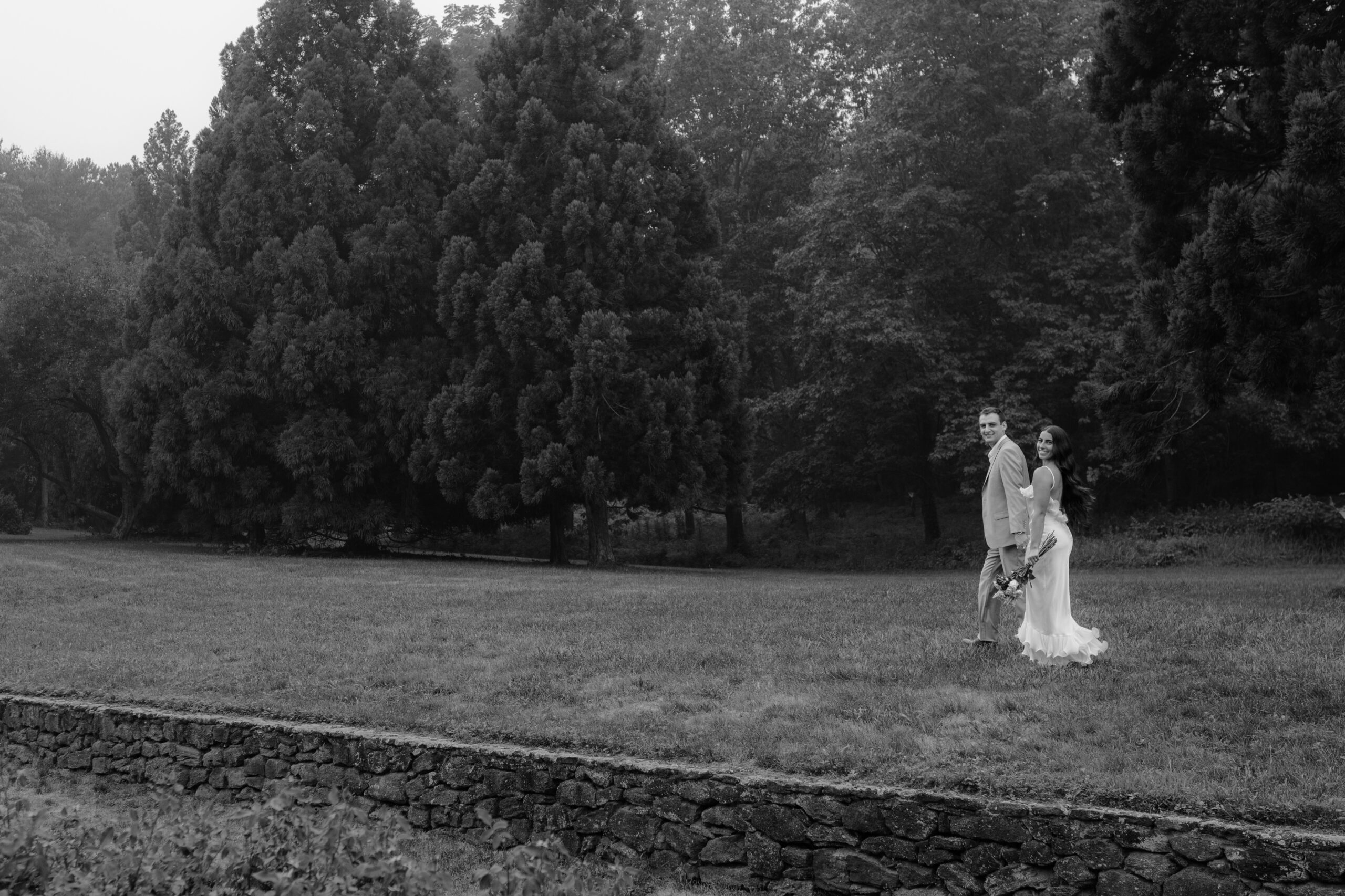 Couple walking in a field on their Deep Cut Gardens & Sandy Hook Beach Engagement Session