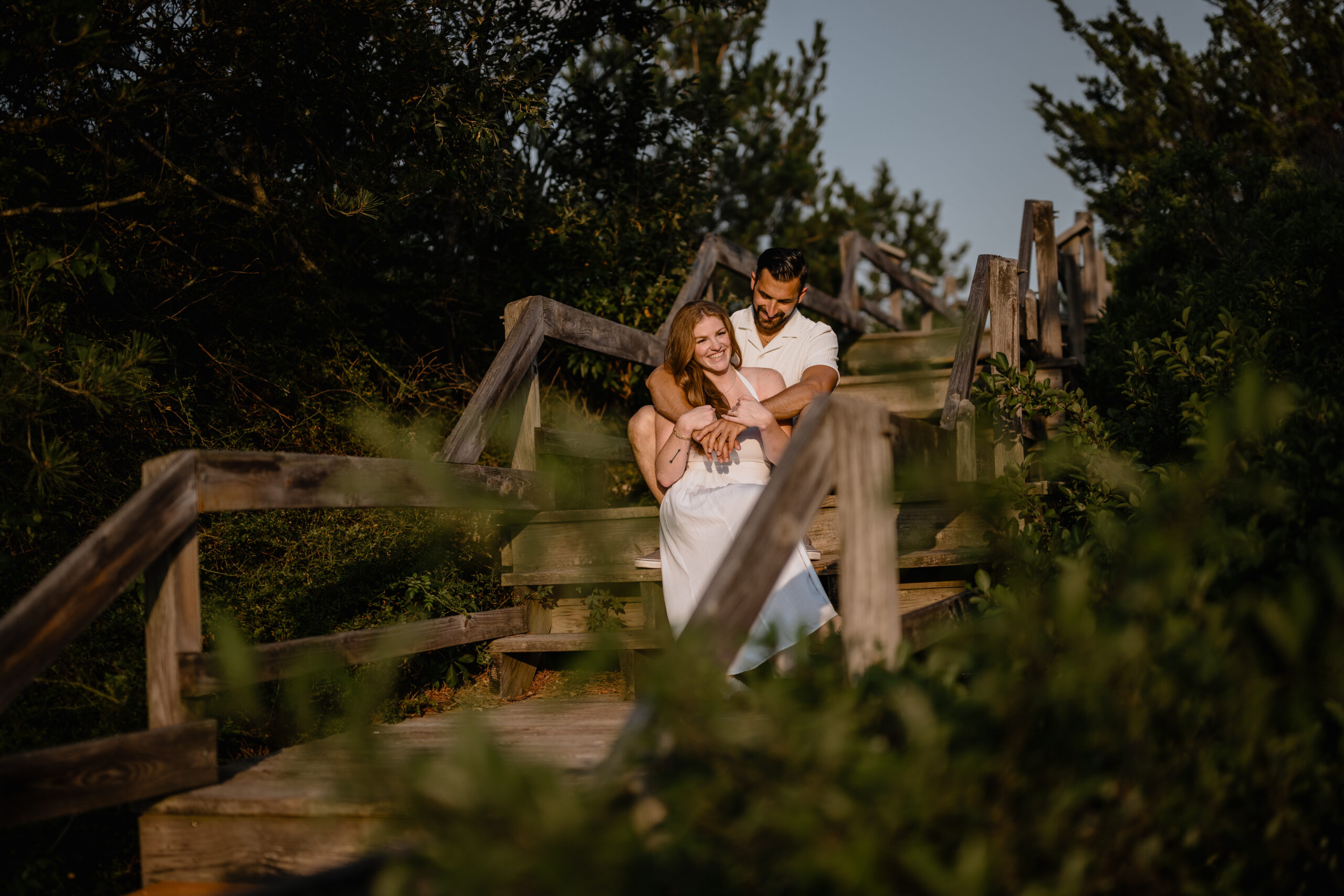 Couple sitting by the wooden stairs during their Engagement Session at Barnegat Lighthouse