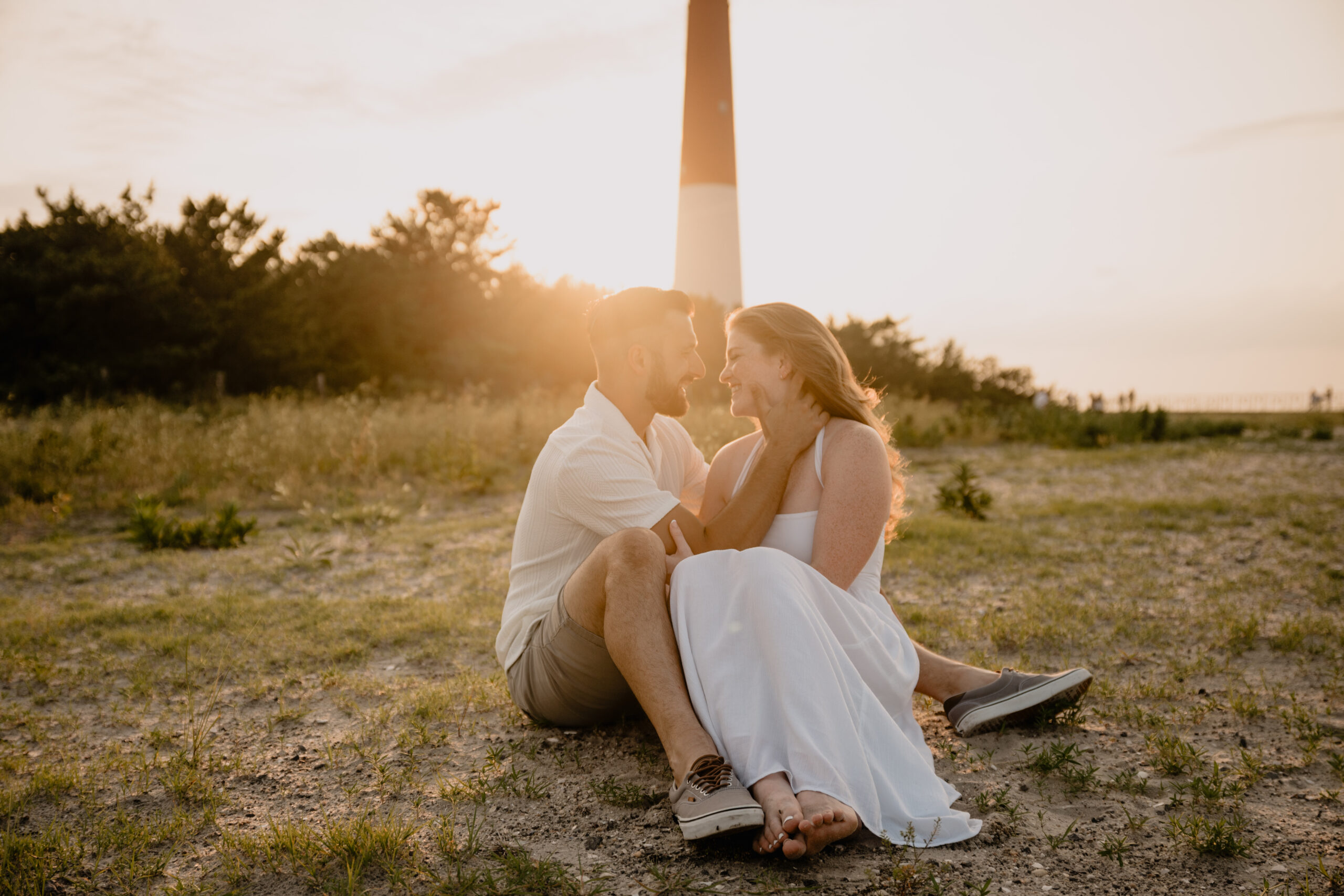 Couple sitting on the ground during their Engagement Session at Barnegat Lighthouse